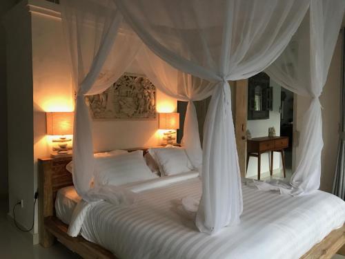 a bedroom with a white bed with a canopy at Balian Bliss Retreat Bungalow & Villas in Balian