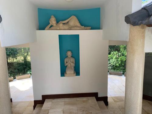 a sculpture of a woman and a statue on a wall at Balian Bliss Retreat Bungalow & Villas in Balian