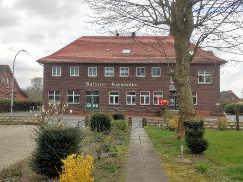 ein großes Backsteingebäude mit einem Baum davor in der Unterkunft Ferienwohnung Alte Schule Ruhwarden in Ruhwarden