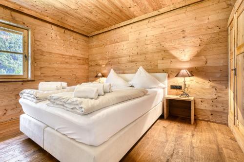 a large white bed in a room with wooden walls at Uralp Royal by A-Appartments in Brand