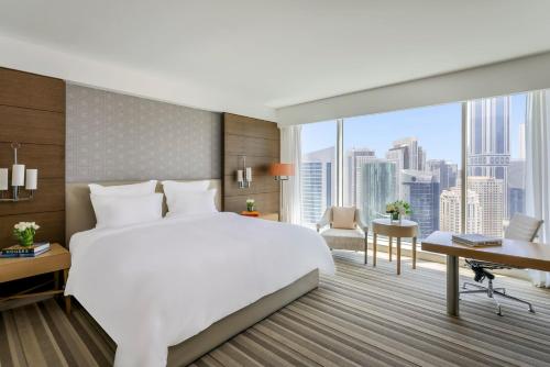 a bedroom with a large white bed and a desk at Pullman Doha West Bay in Doha
