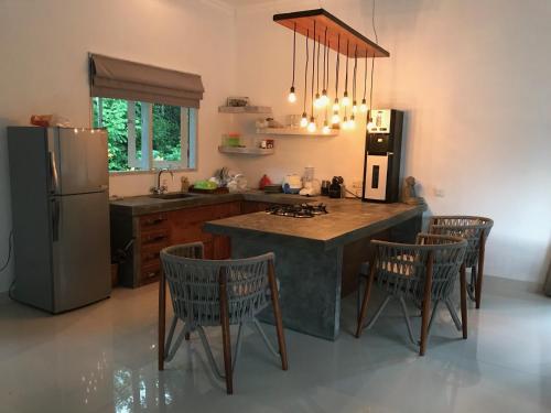 a kitchen with a island with chairs and a refrigerator at Balian Bliss Retreat Bungalow & Villas in Balian