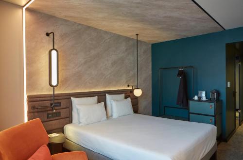 a bedroom with a white bed and an orange chair at Novotel München City in Munich
