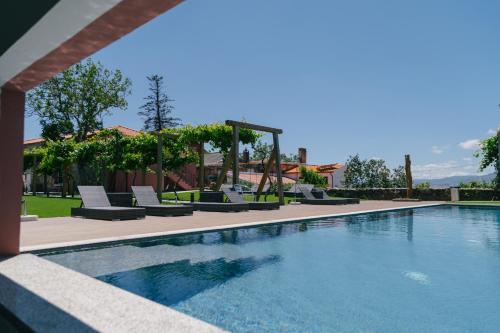 a swimming pool with lounge chairs next to a building at Quinta Vale de Sousa - Douro Valley in Peso da Régua
