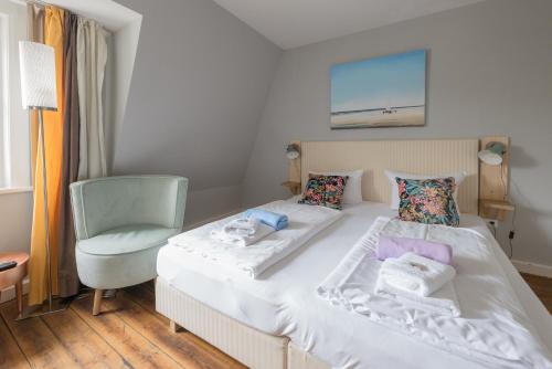 um quarto com uma cama branca e uma cadeira em Hotel 'Das Strandhaus' em Sankt Peter-Ording