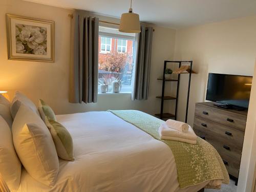 a bedroom with a bed with a television and a window at Number 10 Serviced Apartment - Chapel in Southampton