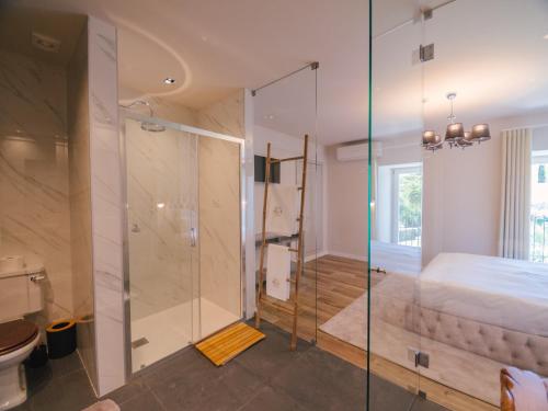 La salle de bains est pourvue d'une douche en verre et d'un lit. dans l'établissement Quinta dos Românticos - Charm House & Wine SPA, à Peso da Régua