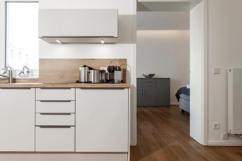 a kitchen with white cabinets and a sink at LIGHTHOUSE APPARTEMENTS in Warnemünde