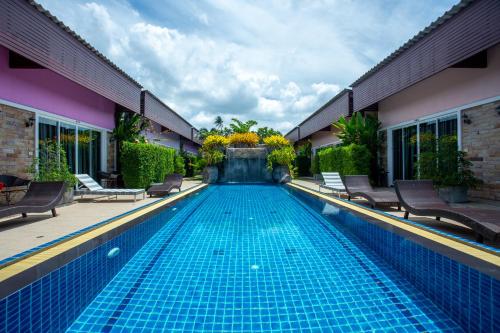 a swimming pool in a house with chairs around it at Areeka Resort Phuket in Thalang