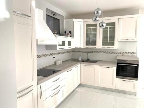 uma cozinha branca com armários e electrodomésticos brancos em La Suite sul Mare 1 em Montesilvano