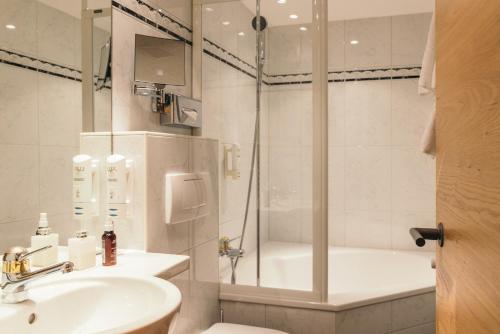 a bathroom with a shower and a sink and a toilet at la couronne Hotel & Spa in Zermatt