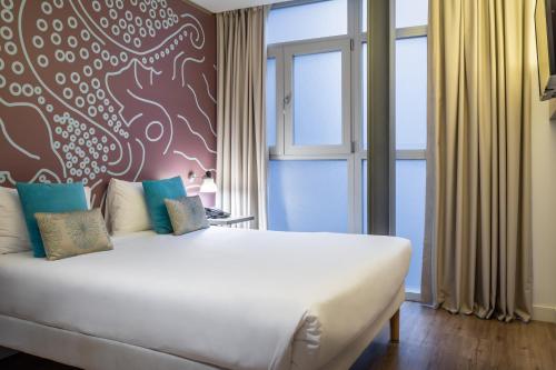 a bedroom with a large white bed and a window at ibis Styles Barcelona Centre in Barcelona