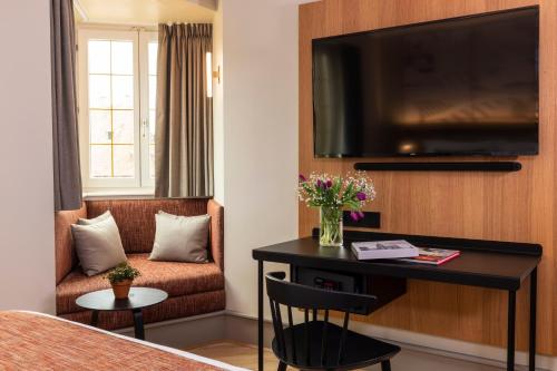 a hotel room with a desk and a tv at Hotel La Diligence in Obernai