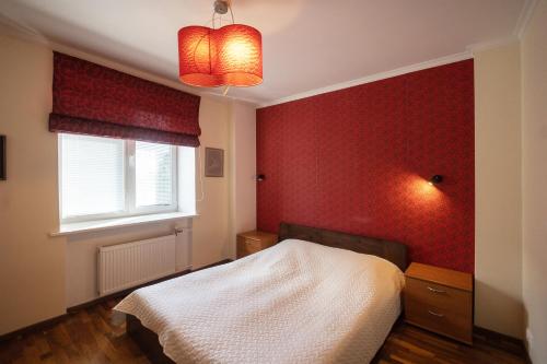 ein Schlafzimmer mit einem Bett und einer roten Wand in der Unterkunft Revalia Airport-Bus Station One-Bedroom Apartment in Tallinn