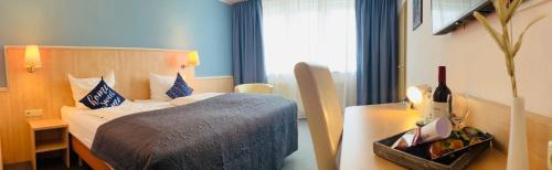 a hotel room with a bed and a table and a window at Konferenzhotel Ysenburger Hof in Langenselbold