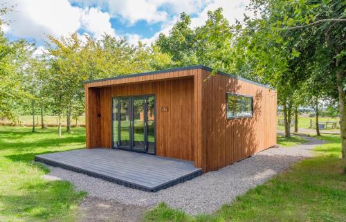 ein kleines Holzgebäude mit einer Tür in einem Park in der Unterkunft Hygge at Vallum in Newcastle upon Tyne