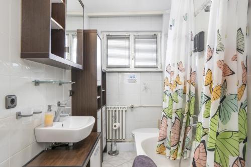 uma casa de banho com um lavatório e uma cortina de chuveiro com borboletas em FREE LIVING - VW näher geht nicht, Parkplatz, Küche, Wlan em Wolfsburg