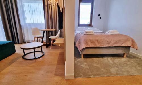 a bedroom with a bed and a table and chairs at Prywatne apartamenty w hotelu - 365PAM in Sarbinowo