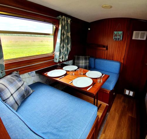 una mesa en un vagón de tren con una mesa y sillas en Narrow Escape - 50ft Boat on the Grand Union Canal, near Tring en Tring