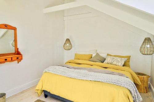 a bedroom with a bed with yellow sheets and a mirror at DE VISSCHUUR in Paternoster