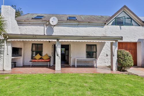 a house with a porch with a bench and a clock at DE VISSCHUUR in Paternoster