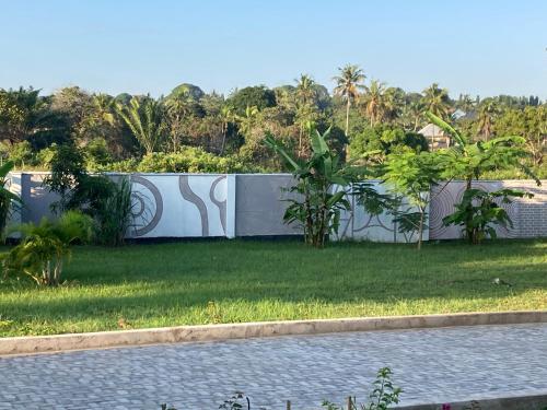 a fence in a yard with grass and trees at Mapeni Lodge in Kidenge