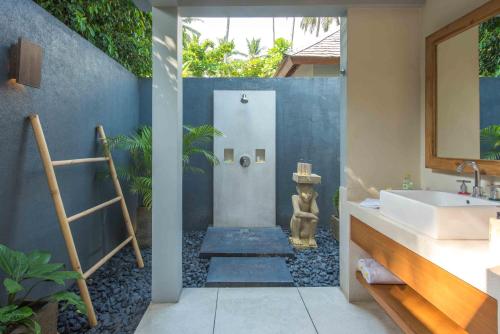 a bathroom with a shower and a sink and a mirror at The Chandi Boutique Resort & Spa in Senggigi