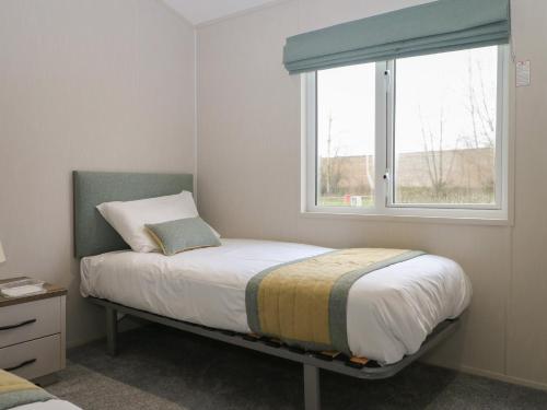 a bedroom with a bed and a window at Lodge at Chichester Lakeside 2 Bed in Chichester