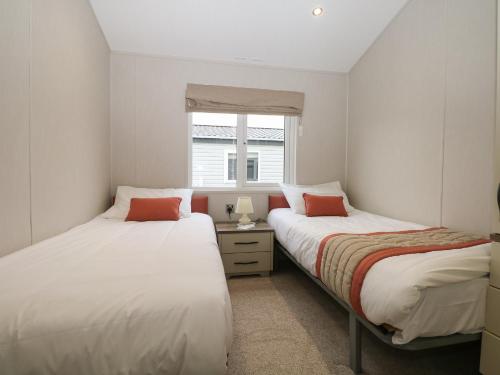 Dos camas en una habitación pequeña con ventana. en Lodge at Chichester Lakeside 3 Bed, en Chichester