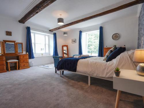 a bedroom with a bed and a dresser and two windows at The Old Bulls Head in Chapel en le Frith