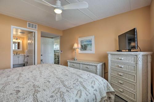 a bedroom with a bed with a television and a dresser at Colorful Oceanside Condo with Beach Access! in Saint Augustine Beach
