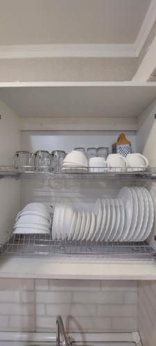 a shelf filled with white plates and bowls at Первая береговая линия in Aktau