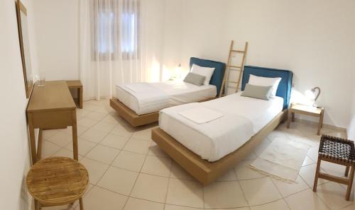 a bedroom with two beds and a table and a desk at Byron House in Parga