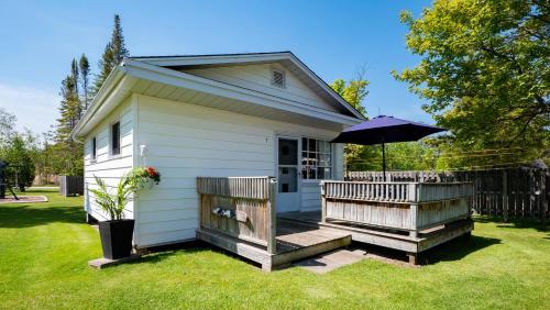 een klein huis met een veranda met een paraplu bij Bel Air Cottages and Motel in Sauble Beach