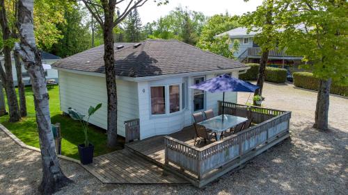 Casa con terraza con mesa y sombrilla en Bel Air Cottages and Motel, en Sauble Beach
