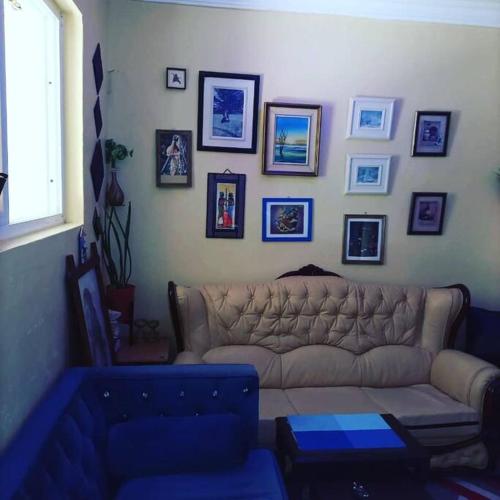 een woonkamer met een bank en foto's aan de muur bij Nimo - One Bedroom Beachroad Deluxe Apartment, Mtwapa in Mombasa