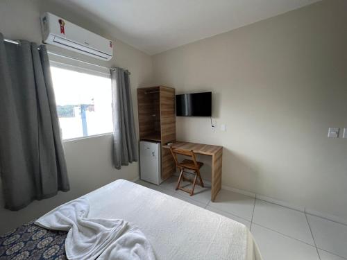 Schlafzimmer mit einem Bett, einem Schreibtisch und einem Fenster in der Unterkunft Pousada Praia Bela in Maragogi