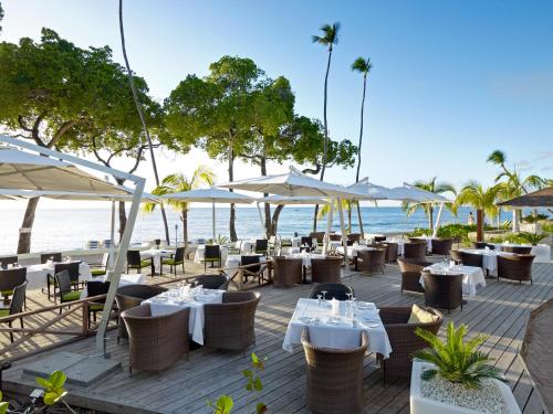 un restaurante en la playa con mesas y sombrillas en Tamarind by Elegant Hotels - All-Inclusive, en Saint James