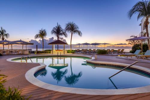 a swimming pool with palm trees and a view of the ocean at Tamarind by Elegant Hotels - All-Inclusive in Saint James