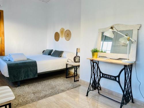 een slaapkamer met een bed en een bureau met een spiegel bij El Rincón de Rita - Benicassim in Benicàssim