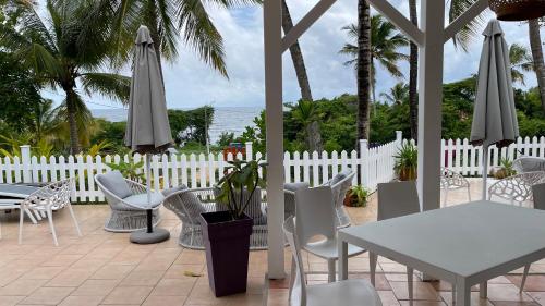 a patio with a white fence and a table and chairs at Le M Hotel Marie Galante in Beauregard