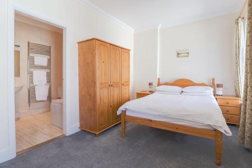 1 dormitorio con 1 cama y armario de madera en Falcon's Nest Hotel en Port Erin
