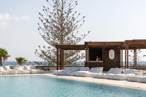 a pool with white lounge chairs next to a swimming pool at Helea Lifestyle Beach Resort in Kallithea Rhodes