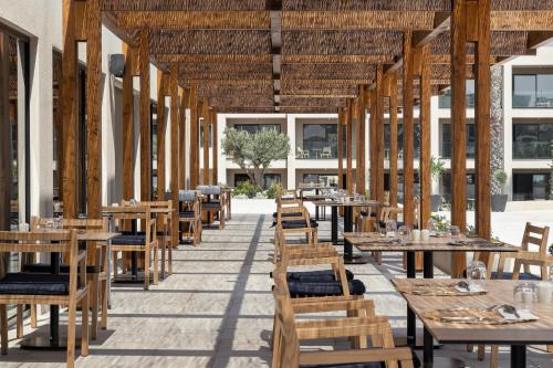 an empty restaurant with wooden tables and chairs at Helea Lifestyle Beach Resort in Kallithea Rhodes