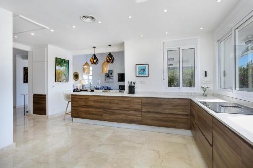 a large kitchen with white walls and wood cabinets at Villa La Perla by Finest Rentals in Marbella