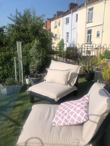 a patio with a couch and pillows on the grass at The Cottage, Ashfield Place in Bristol