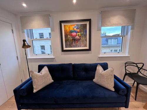 a blue couch in a living room with a painting at Chapel - Central Studio Apartment in Bath