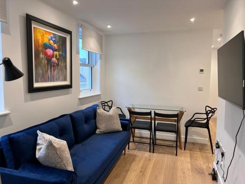 a living room with a blue couch and a table at Chapel - Central Studio Apartment in Bath