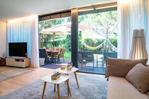 a living room with a couch and a tv and a table at Home Six Troia in Carvalhal