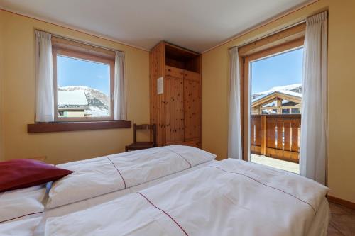a bedroom with a large bed and two windows at Hotel San Rocco in Livigno